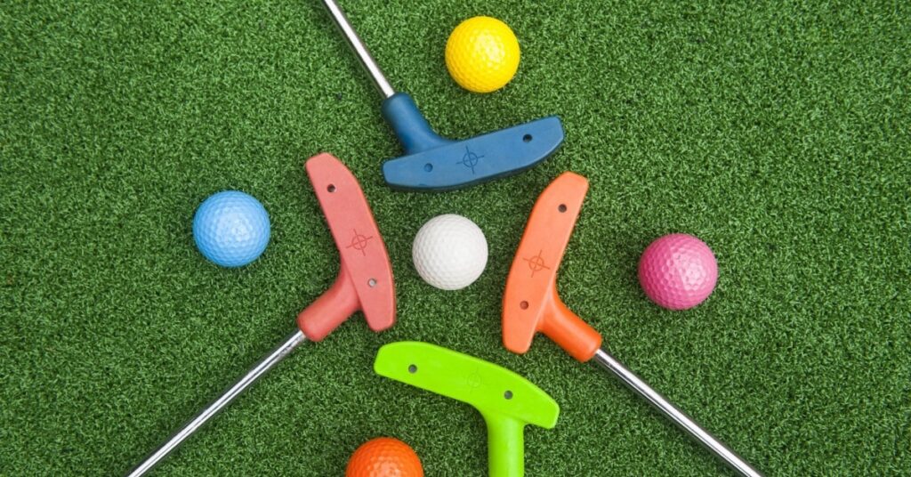 putters and golf balls on the green at a mini-golf location in the Kawartha Lakes